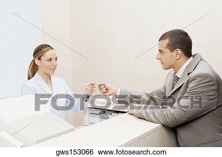 Customer giving a credit card to a female receptionist View Large Photo Image Stock Photograph - Customer giving a credit card to a female receptionist. Fotosearch