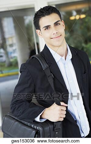 Stock Photograph - Portrait of a businessman carrying a bag and smiling. Fotosearch