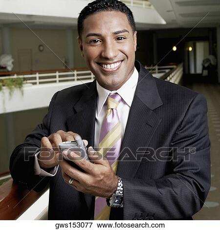 Stock Photo - Portrait of a businessman holding a personal data assistant and smiling. Fotosearch