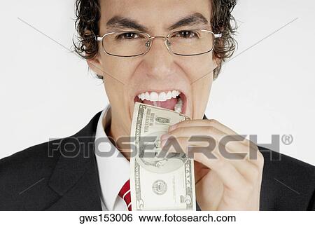 Portrait of a businessman putting a dollar bill into his mouth View Large Photo Image Stock Photograph - Portrait of a businessman putting a dollar bill into his mouth. Fotosearch