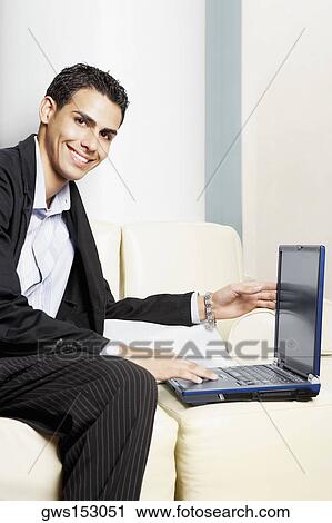 Stock Image - Portrait of a businessman sitting on a couch with a laptop. Fotosearch