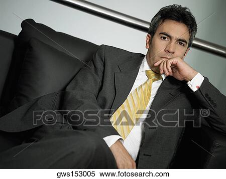 Portrait of a businessman sitting on a couch with his legs crossed View Large Photo Image Stock Photography - Portrait of a businessman sitting on a couch with his legs crossed. Fotosearch