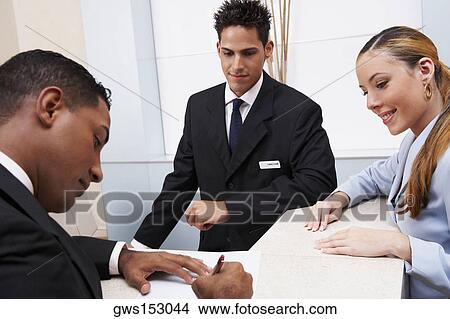 Side profile of a businessman writing on paper with business executives looking at him View Large Photo Image Picture - Side profile of a businessman writing on paper with business executives looking at him. Fotosearch