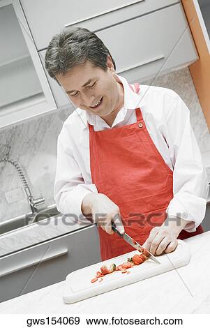 Close-up of a mature man cutting vegetables in the kitchen View Large Photo Image Stock Photo - Close-up of a mature man cutting vegetables in the kitchen. Fotosearch