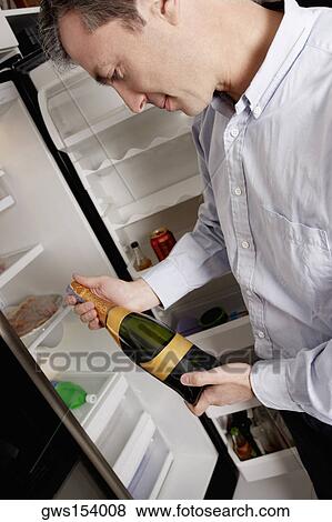 Stock Photo - Close-up of a mature man looking at a beer bottle. Fotosearch