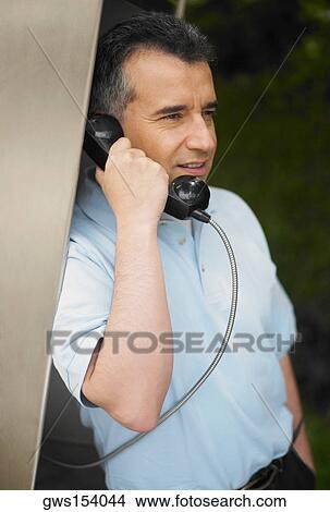 Close-up of a mid adult man talking on a pay phone View Large Photo Image Picture - Close-up of a mid adult man talking on a pay phone. Fotosearch