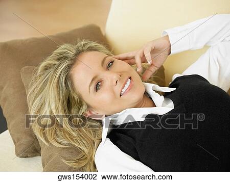 High angle view of a mid adult woman lying on a couch and smiling View Large Photo Image Stock Image - High angle view of a mid adult woman lying on a couch and smiling. Fotosearch