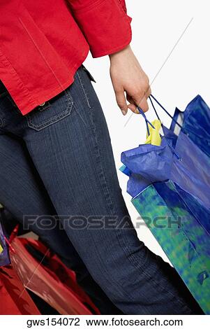 Low section view of a woman holding shopping bags View Large Photo Image Stock Image - Low section view of a woman holding shopping bags. Fotosearch