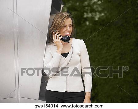 Mid adult woman talking on a pay phone View Large Photo Image Picture - Mid adult woman talking on a pay phone. Fotosearch