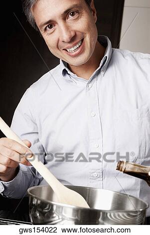 Portrait of a mature man preparing food in the kitchen and smiling View Large Photo Image Stock Image - Portrait of a mature man preparing food in the kitchen and smiling. Fotosearch