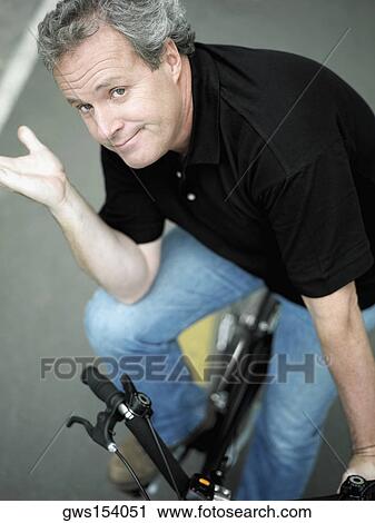 Portrait of a mature man sitting on a bicycle and gesturing View Large Photo Image Stock Image - Portrait of a mature man sitting on a bicycle and gesturing. Fotosearch