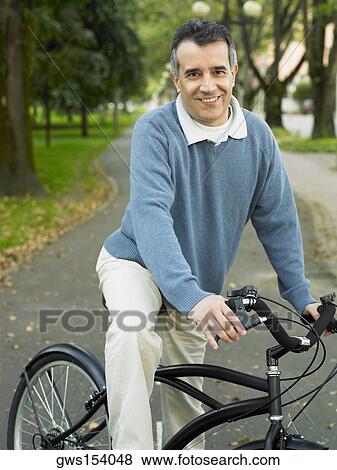 Portrait of a mid adult man cycling in a park View Large Photo Image Stock Photo - Portrait of a mid adult man cycling in a park. Fotosearch