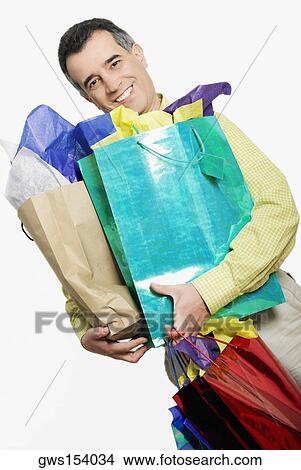 Portrait of a mid adult man holding a shopping bag and smiling View Large Photo Image Picture - Portrait of a mid adult man holding a shopping bag and smiling. Fotosearch