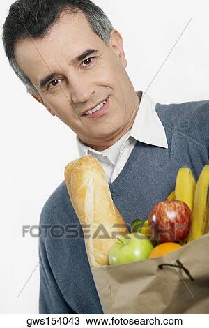 Stock Image - Portrait of a mid adult man holding a shopping bag. Fotosearch