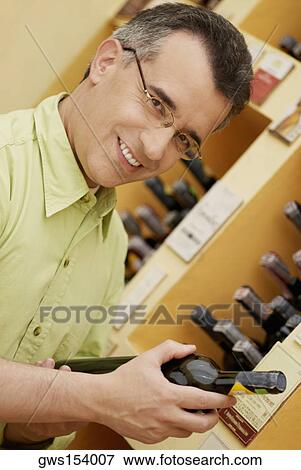Portrait of a mid adult man holding a wine bottle View Large Photo Image Stock Photo - Portrait of a mid adult man holding a wine bottle. Fotosearch