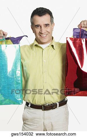 Portrait of a mid adult man holding shopping bags View Large Photo Image Stock Image - Portrait of a mid adult man holding shopping bags. Fotosearch