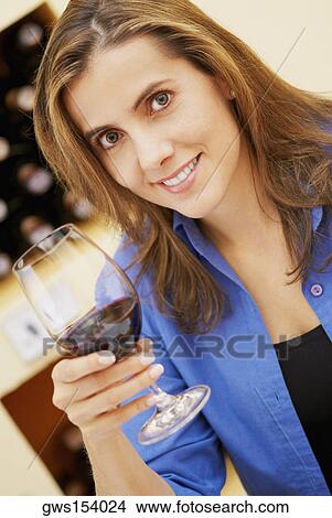 Picture - Portrait of a mid adult woman holding a glass of red wine. Fotosearch
