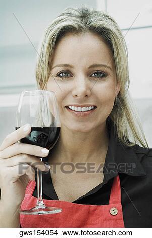 Portrait of a mid adult woman holding a glass of red wine and smiling View Large Photo Image Picture - Portrait of a mid adult woman holding a glass of red wine and smiling. Fotosearch