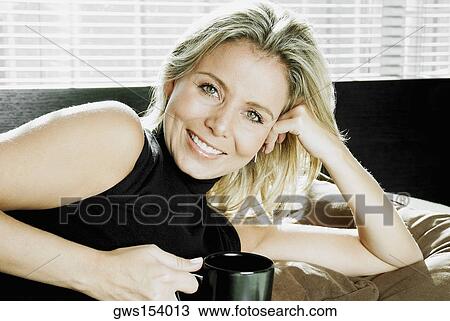 Portrait of a mid adult woman lying on the bed and holding a cup of coffee View Large Photo Image Stock Image - Portrait of a mid adult woman lying on the bed and holding a cup of coffee. Fotosearch