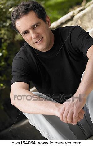 Portrait of a young man sitting with his hands clasped View Large Photo Image Picture - Portrait of a young man sitting with his hands clasped. Fotosearch