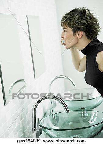 Stock Photo - Side profile of a mature woman brushing her teeth. Fotosearch