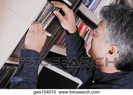 Stock Photography - Side profile of a senior man looking for a CD. Fotosearch
