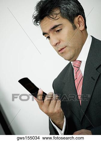Picture - Close-up of a businessman looking at a mobile phone. Fotosearch