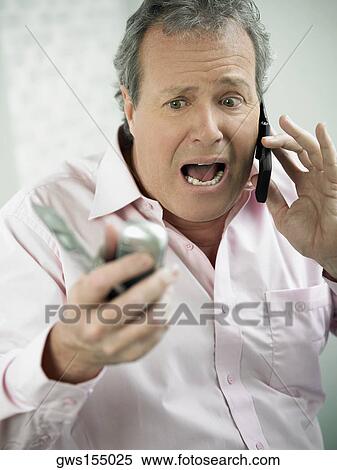 Close-up of a mature man shouting on a mobile phone and holding two mobile phones in his other hand View Large Photo Image Stock Photography - Close-up of a mature man shouting on a mobile phone and holding two mobile phones in his other hand. Fotosearch