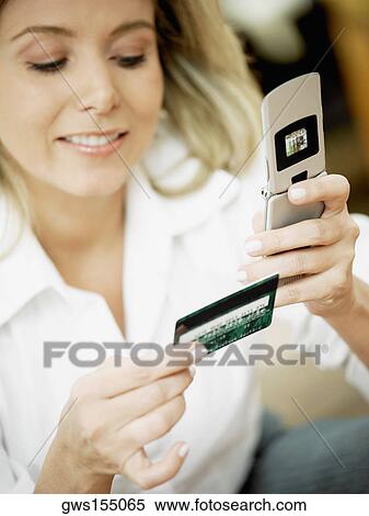 Close-up of a mid adult woman holding a mobile phone and a credit card View Large Photo Image Stock Photography - Close-up of a mid adult woman holding a mobile phone and a credit card. Fotosearch