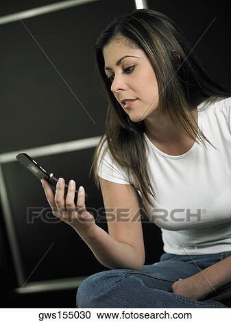 Stock Image - Close-up of a mid adult woman looking at a mobile phone. Fotosearch