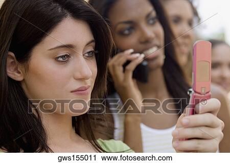 Stock Image - Close-up of a teenage girl holding a mobile phone and thinking. Fotosearch