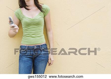 Stock Image - Mid section view of a teenage girl holding a mobile phone. Fotosearch