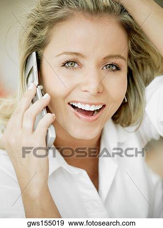 Stock Photo - Portrait of a mid adult woman talking on a mobile phone and smiling. Fotosearch