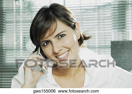 Portrait of a mid adult woman talking on a mobile phone and smiling View Large Photo Image Stock Photograph - Portrait of a mid adult woman talking on a mobile phone and smiling. Fotosearch
