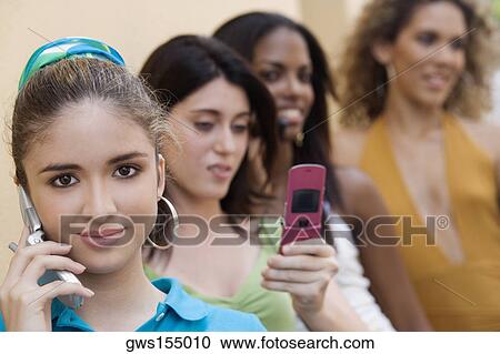 Portrait of a teenage girl talking on a mobile phone with three teenage girls behind her View Large Photo Image Stock Image - Portrait of a teenage girl talking on a mobile phone with three teenage girls behind her. Fotosearch