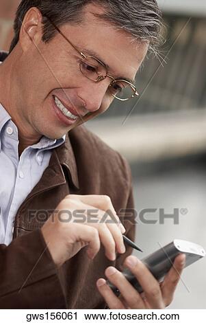 Stock Image - Close-up of a businessman operating a hand held device with a digitized pen. Fotosearch