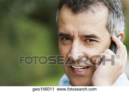 Stock Image - Close-up of a mid adult man talking on a mobile phone. Fotosearch