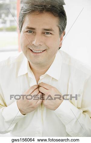Portrait of a mature man buttoning his shirt and smiling View Large Photo Image Picture - Portrait of a mature man buttoning his shirt and smiling. Fotosearch