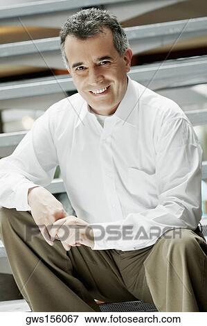 Stock Photo - Portrait of a mid adult man sitting on steps. Fotosearch