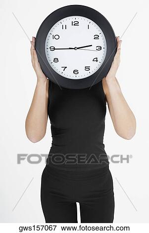 Businesswoman hiding her face with a clock View Large Photo Image Stock Photo - Businesswoman hiding her face with a clock. Fotosearch