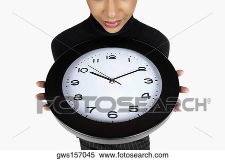 Close-up of a businesswoman holding a clock View Large Photo Image Stock Photography - Close-up of a businesswoman holding a clock. Fotosearch