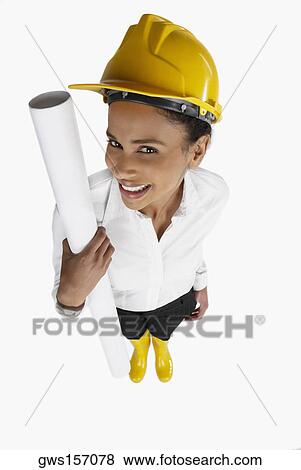 High angle view of a female architect holding a blueprint and smiling View Large Photo Image Stock Photo - High angle view of a female architect holding a blueprint and smiling. Fotosearch