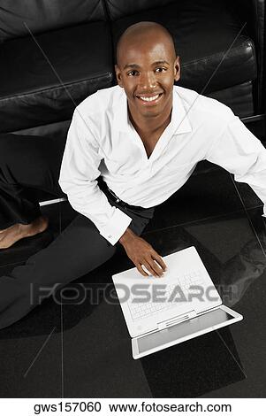 Stock Image - High angle view of a young man using a laptop. Fotosearch