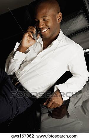 High angle view of a young man using a mobile phone and smiling View Large Photo Image Stock Image - High angle view of a young man using a mobile phone and smiling. Fotosearch