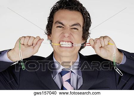 Portrait of a businessman biting a chain of paper clips View Large Photo Image Stock Image - Portrait of a businessman biting a chain of paper clips. Fotosearch