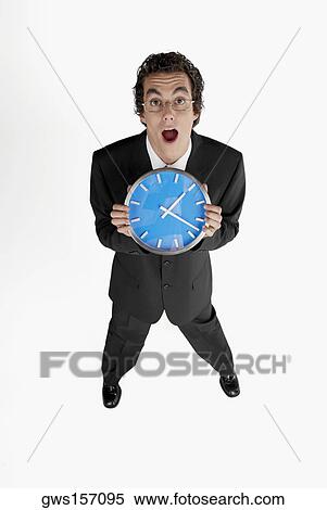Stock Photography - Portrait of a businessman holding a clock. Fotosearch