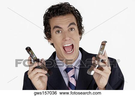 Portrait of a businessman holding mobile phones View Large Photo Image Stock Photograph - Portrait of a businessman holding mobile phones. Fotosearch