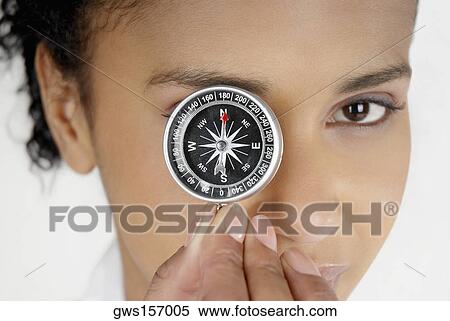 Stock Photography - Portrait of a businesswoman covering her eye with a compass. Fotosearch