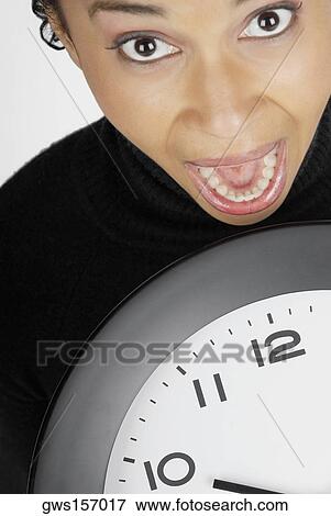 Portrait of a businesswoman holding a clock with her mouth open View Large Photo Image Stock Photo - Portrait of a businesswoman holding a clock with her mouth open. Fotosearch