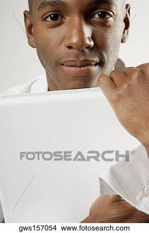 Portrait of a young man holding a laptop View Large Photo Image Picture - Portrait of a young man holding a laptop. Fotosearch